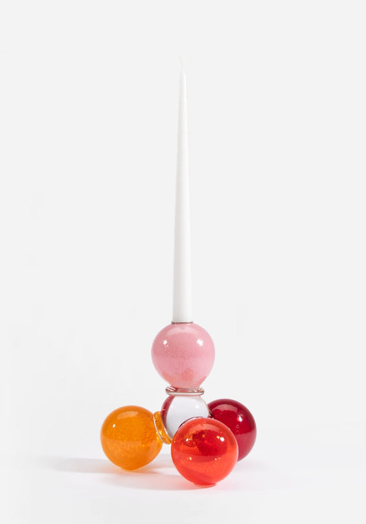 Munblåst ljusstake i glas av Åsa Gårdebäck, uppbyggd av färgglada glasbollar i rosa, röda och orangea toner med ett stearinljus i.