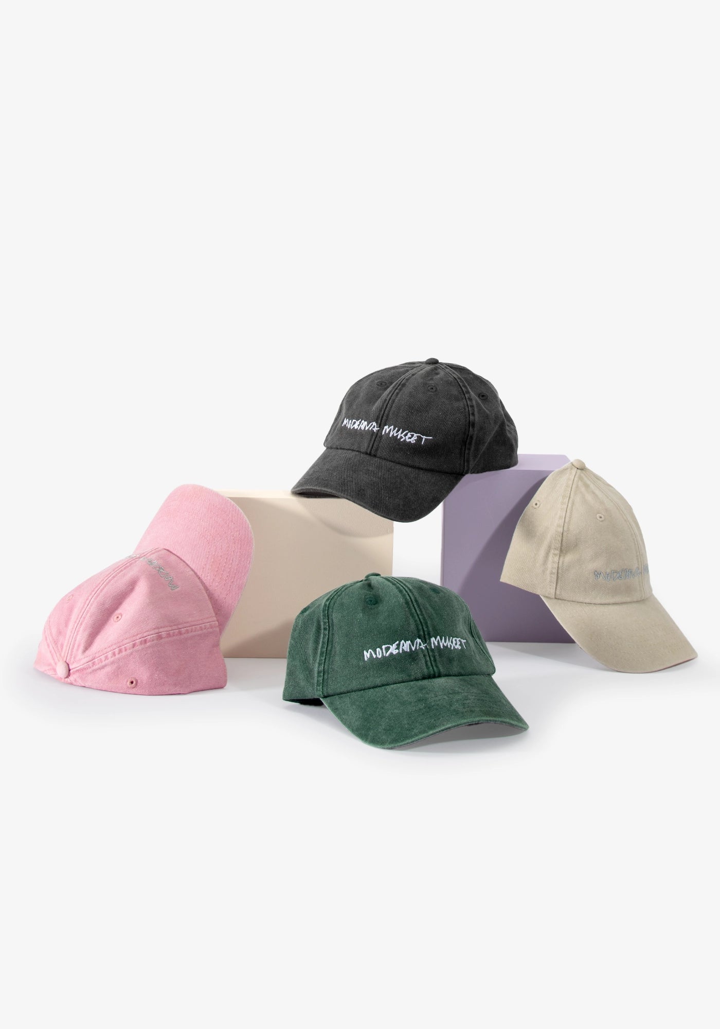 Kepsar Moderna Museet i fyra färger — rosa, grön, grå och sand — med broderad logotyp