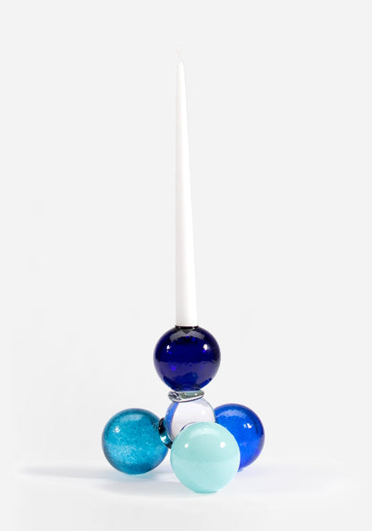 Munblåst ljusstake i glas av Åsa Gårdebäck, uppbyggd av färgglada glasbollar i olika blåa toner. En lekfull ljusstake med mycket karaktär.