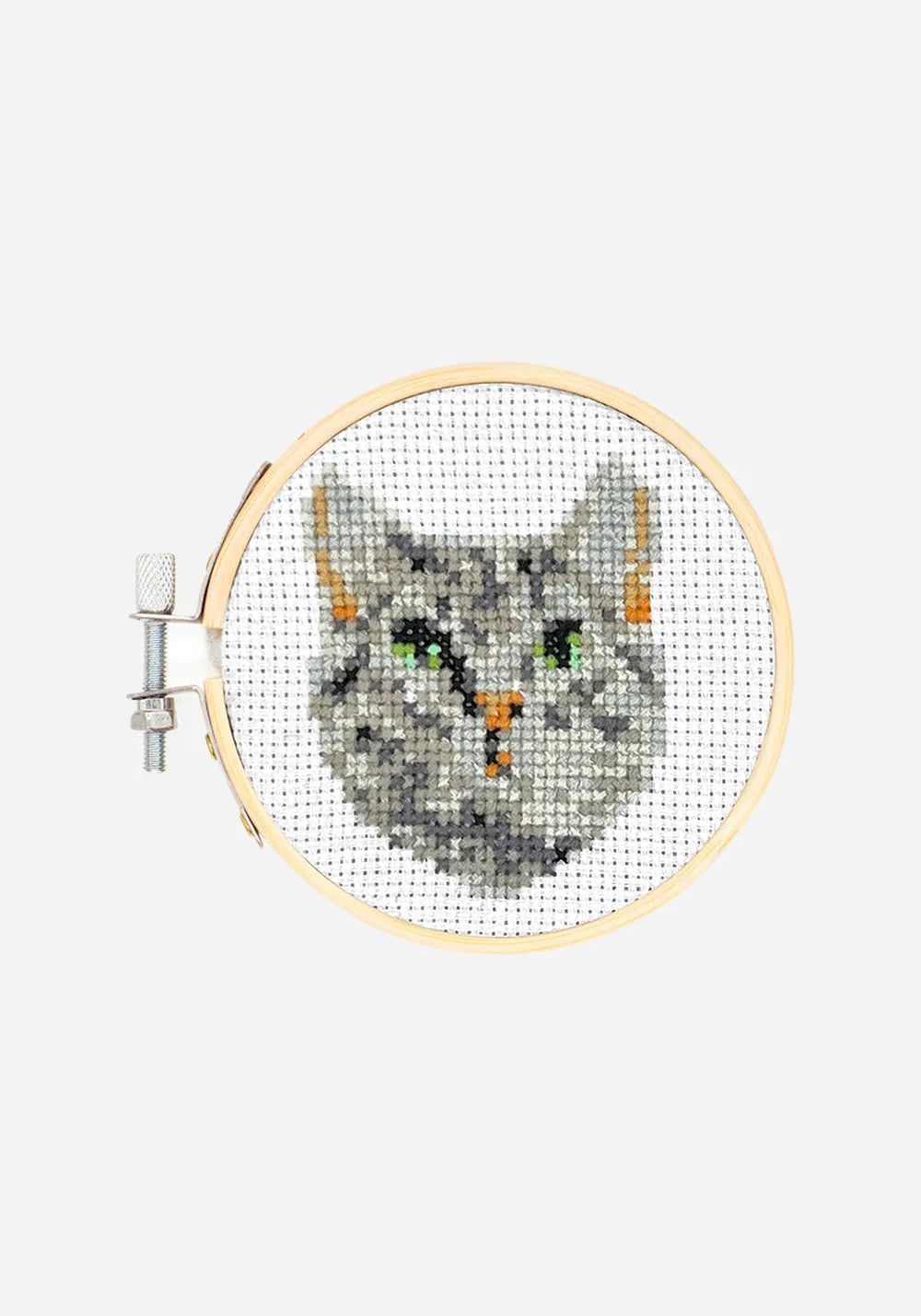 Färdigt korsstygnsbroderi i en broderiram i bambu, med ett grårandigt kattansikte med gröna ögon och orange nos.