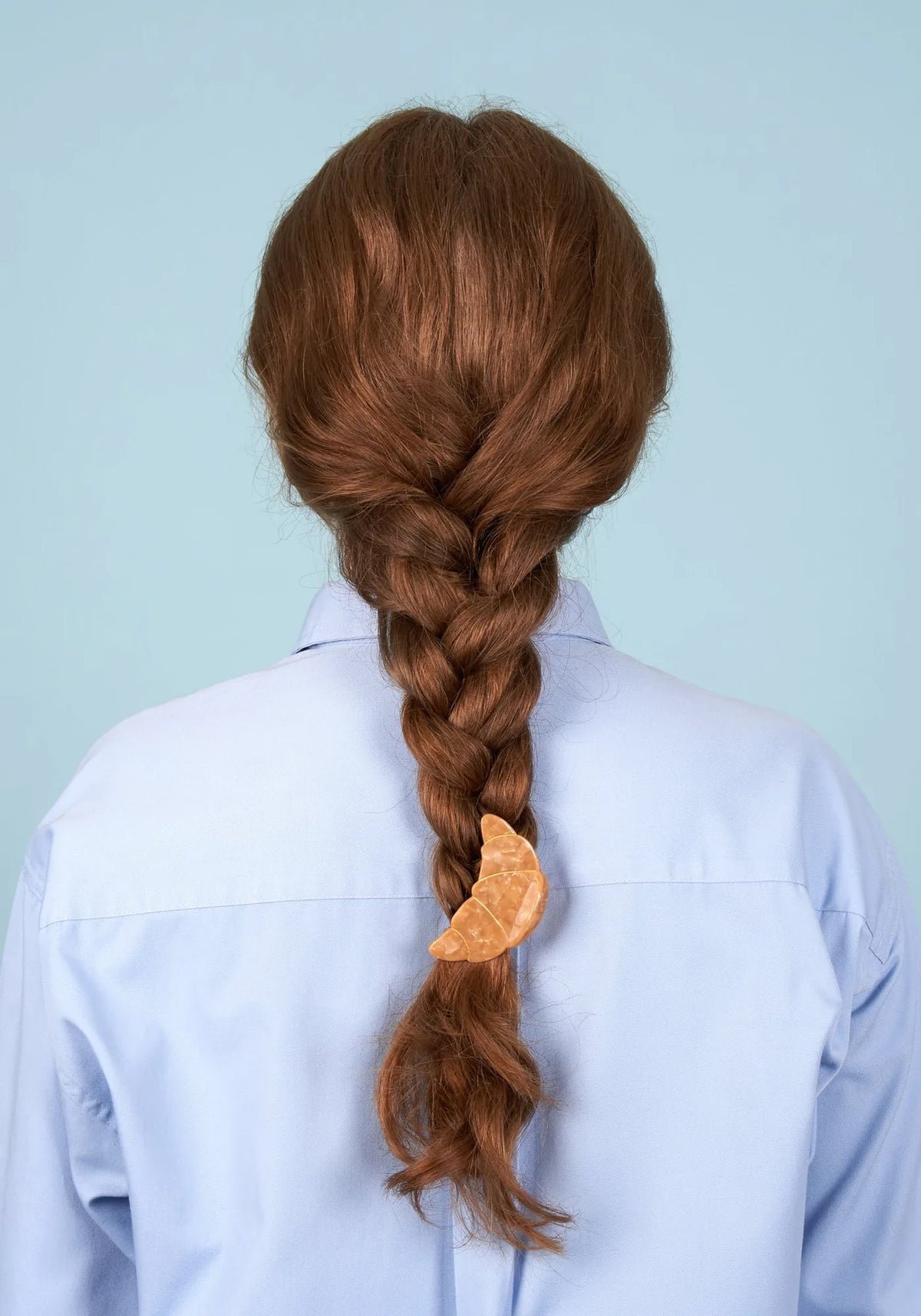 Kvinna i profil med långa locs uppsatta i en halvuppsättning, hållen av en croissantformad hårklämma från Coucou Suzette