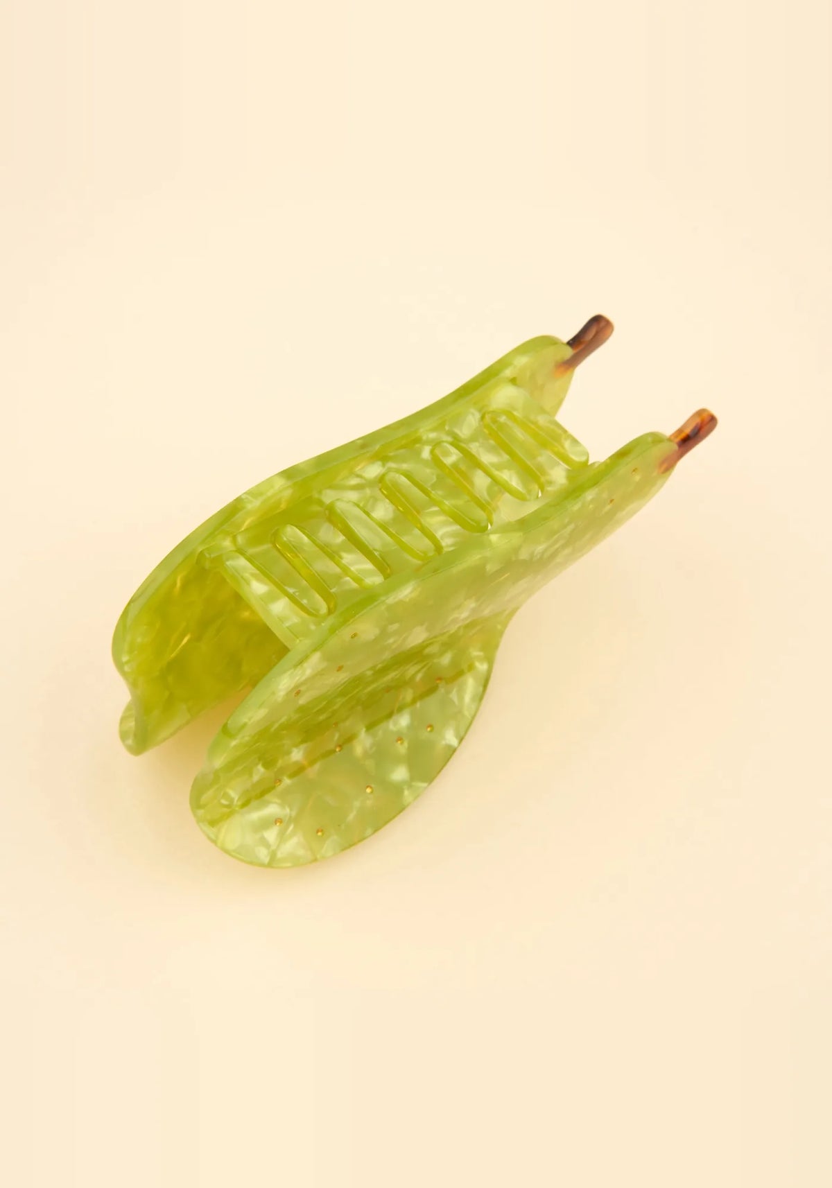 Grön päronformad hårklo från Coucou Suzette sedd snett ovanifrån, med tänderna i acetat synliga