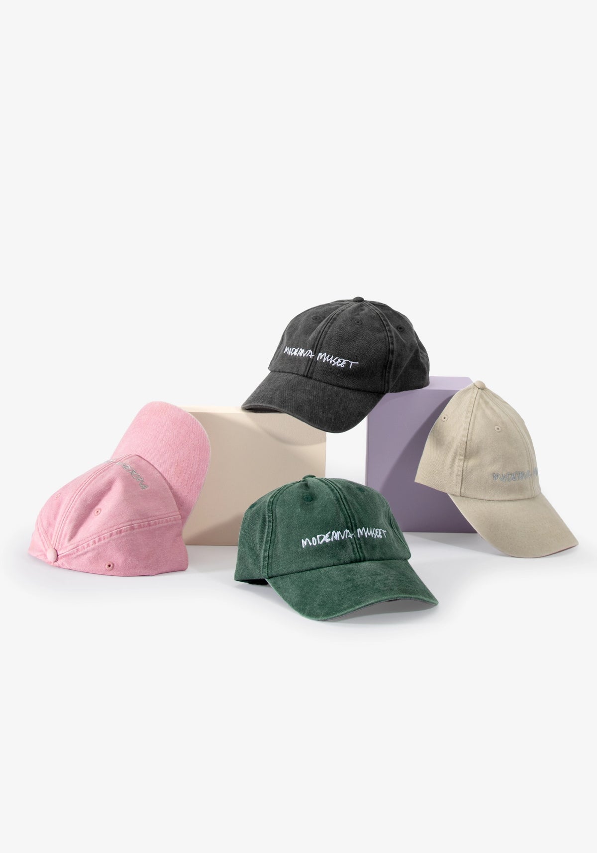 Kepsar Moderna Museet i fyra färger — rosa, grön, grå och sand — med broderad logotyp