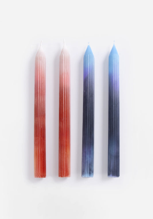 Fyra räfflade kronljus, två i orange och två i blå färgtoning, liggande mot vit bakgrund.