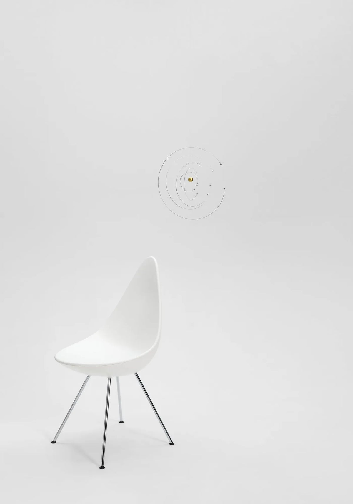 Niels Bohr-mobilen från Flensted hänger ovanför en vit stol i ett ljust rum