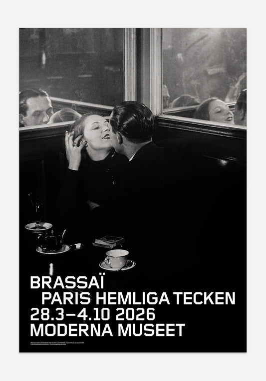 Svartvit utställningsaffisch från Moderna Museet för Brassaï-utställningen Paris hemliga tecken. Motivet visar ett stämningsfullt fotografi av ett kyssande par i en cafésoffa, med tekoppar på bordet och speglande glas i bakgrunden.
