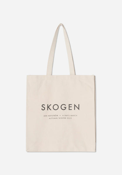 Naturvit tygkasse med texten SKOGEN i stora grå versaler, och under den Jan Håfström × A Day’s March, Autumn/Winter 2025.